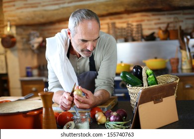 Mature man in kitchen reading recipe on tablet - Powered by Shutterstock