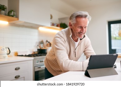 Mature Man In Kitchen Working From Home Using Digital Tablet - Powered by Shutterstock