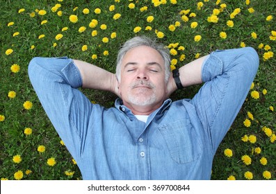 Mature Man Laying On His Back In A Field Of Flowers.