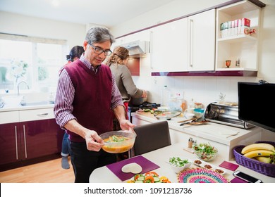 Mature Man Is Laying The Table Ready For His Family To Share Dinner Together. 