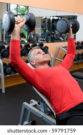 Mature Man Lifting Dumbells At Fitness Gym