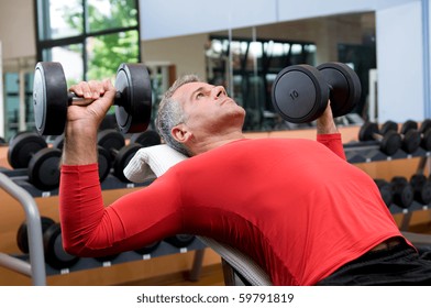 Mature Man Lifting Dumbells At Fitness Gym