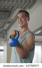 Mature Man Lifting Weights In The Gym