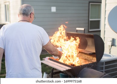 Mature Man Lighting Barbecue With Lighter Fluid