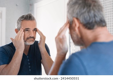 Mature man looking in bathroom mirror - Powered by Shutterstock