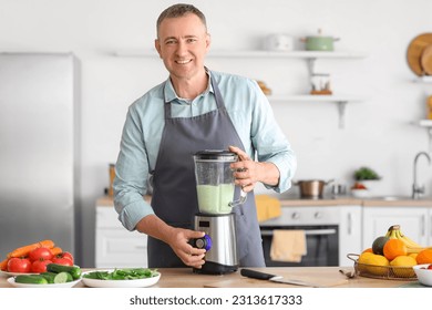 Mature man making smoothie with blender in kitchen - Powered by Shutterstock