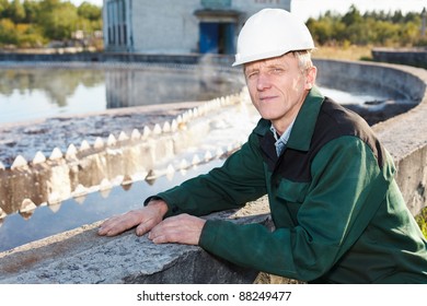 Mature Man Manual Worker In White Hardhat Near Sewage Treatment Basin