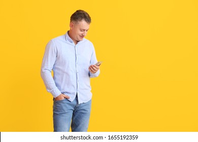 Mature Man With Mobile Phone On Color Background