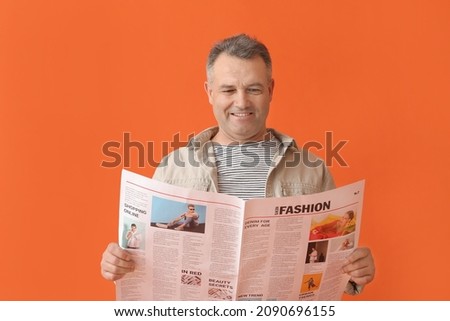 Mature man with newspaper on color background