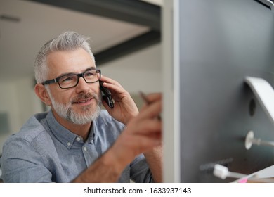 Mature Man In Office Talking On Phone 