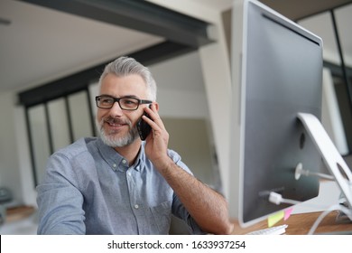 Mature Man In Office Talking On Phone 