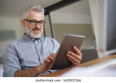 Mature Man In Office Working With Digital Tablet