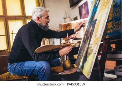 Mature man painting on canvas in art studio. - Powered by Shutterstock