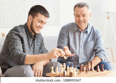 Mature Man Playing Chess With His Son At Home