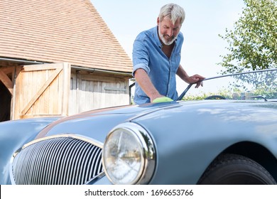 Mature Man Polishing Restored Classic Sports Car Outdoors At Home       - Shutterstock ID 1696653766