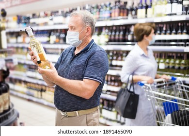 Mature Man In Protective Mask Buying Bottle Of Wine In Store With Alcohol Drinks