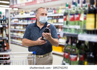 Mature Man In Protective Mask Buying Bottle Of Wine In Store With Alcohol Drinks