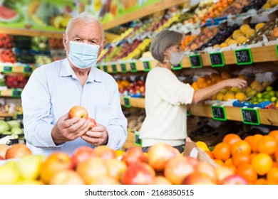 Mature Man In Protective Mask Choosing Sweet Apples And Other Fruit On Counter Of Farmers Market