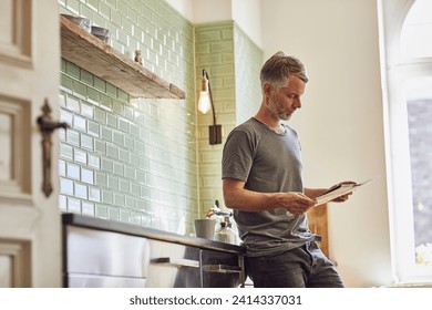 Mature man reading newspaper in kitchen at home - Powered by Shutterstock