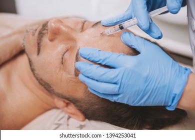 Mature man receiving facial filler injections by professional cosmetologist. Mid-aged man getting anti-wrinkle treatment at beauty salon. Botox, disport filler concept - Shutterstock ID 1394253041