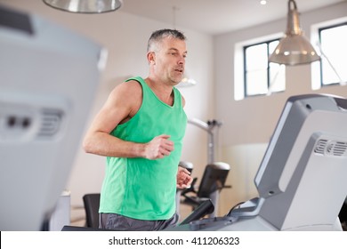 Mature Man Running On Treadmill In Gym