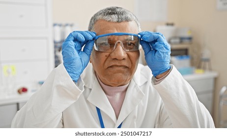 A mature man scientist adjusts protective goggles in a laboratory setting. - Powered by Shutterstock