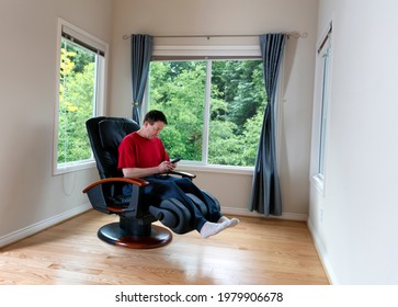 Mature Man Selecting Program On Home Massage Chair For Pain Relief  