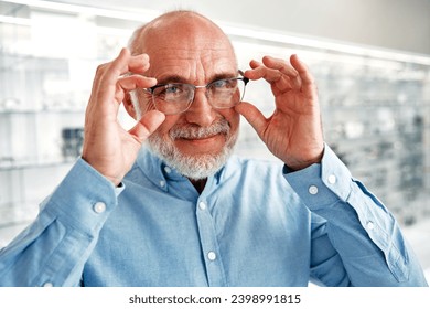 Mature man senior choosing optical glasses for himself in a professional store. Vision correction and ophthalmology. - Powered by Shutterstock