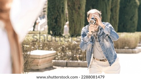 Mature man shooting video in city park with vintage camera