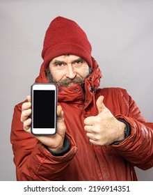 Mature Man Showing Smart Phone Screen Into Camera In Thick Winter Coat At Freezing Cold Temperatures