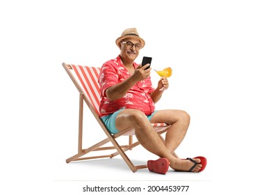 Mature Man Sitting On A Beach Chair With A Smartphone And A Cocktail Isolated On White Background