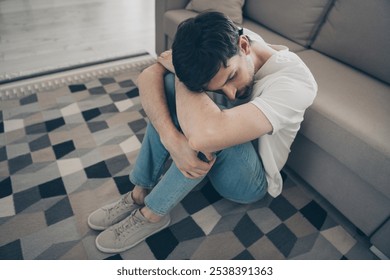 Mature man sitting on floor at home, reflecting introspectively during leisure time on a quiet weekend indoors - Powered by Shutterstock