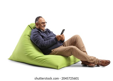 Mature Man Sitting On A Green Bean Bag Chair And Using A Mobile Phone Isolated On White Background