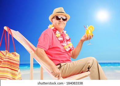 Mature Man Sitting On Sun Lounger And Drinking Cocktail On A Sunny Beach