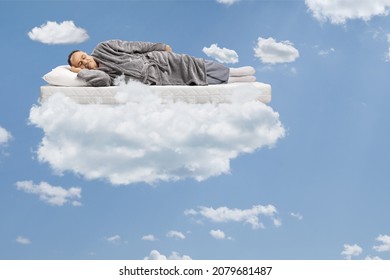 Mature Man Sleeping On A Matress And Floating In A Blue Sky With Clouds