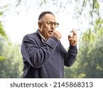 Mature man smoking and coughing outdoors in a park