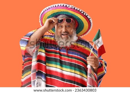 Mature man in sombrero hat with Mexican flag on orange background