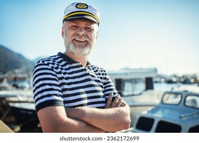 Mature man standing near the sea dressed in a sailor's shirt and hat.