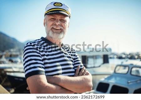 Mature man standing near the sea dressed in a sailor's shirt and hat.