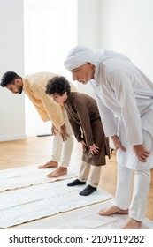 Mature man standing on rug near arabian family at home