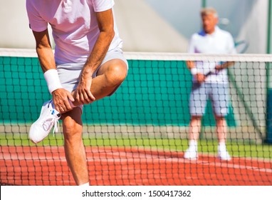 Mature Man Standing While Suffering From Leg Pain During Match At Tennis Court