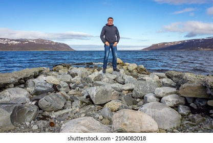 A Mature man stands on a rocky beach - Powered by Shutterstock