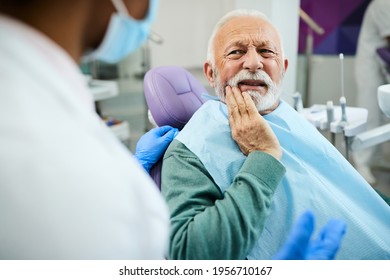 Mature man talking about toothache problems with his dentist at dental clinic. 