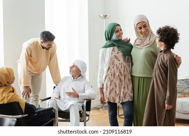 mature man talking to adult son near multiethnic muslim family at home