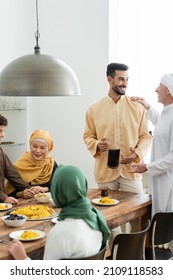 Mature man talking to araban son near interracial muslim family and food at home