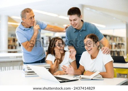 Mature man tells a group of young students to be quiet in the library