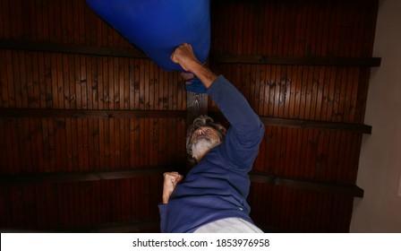 Mature Man Training With A Punching Bag At His Home