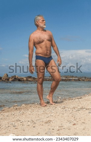 mature man in the tropical beach with blue speedo