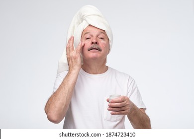 Mature Man Using Cream For Face Skin. Studio Shot