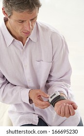 Mature Man Using A Home Blood Pressure Machine To Check His Vital Statistics.  